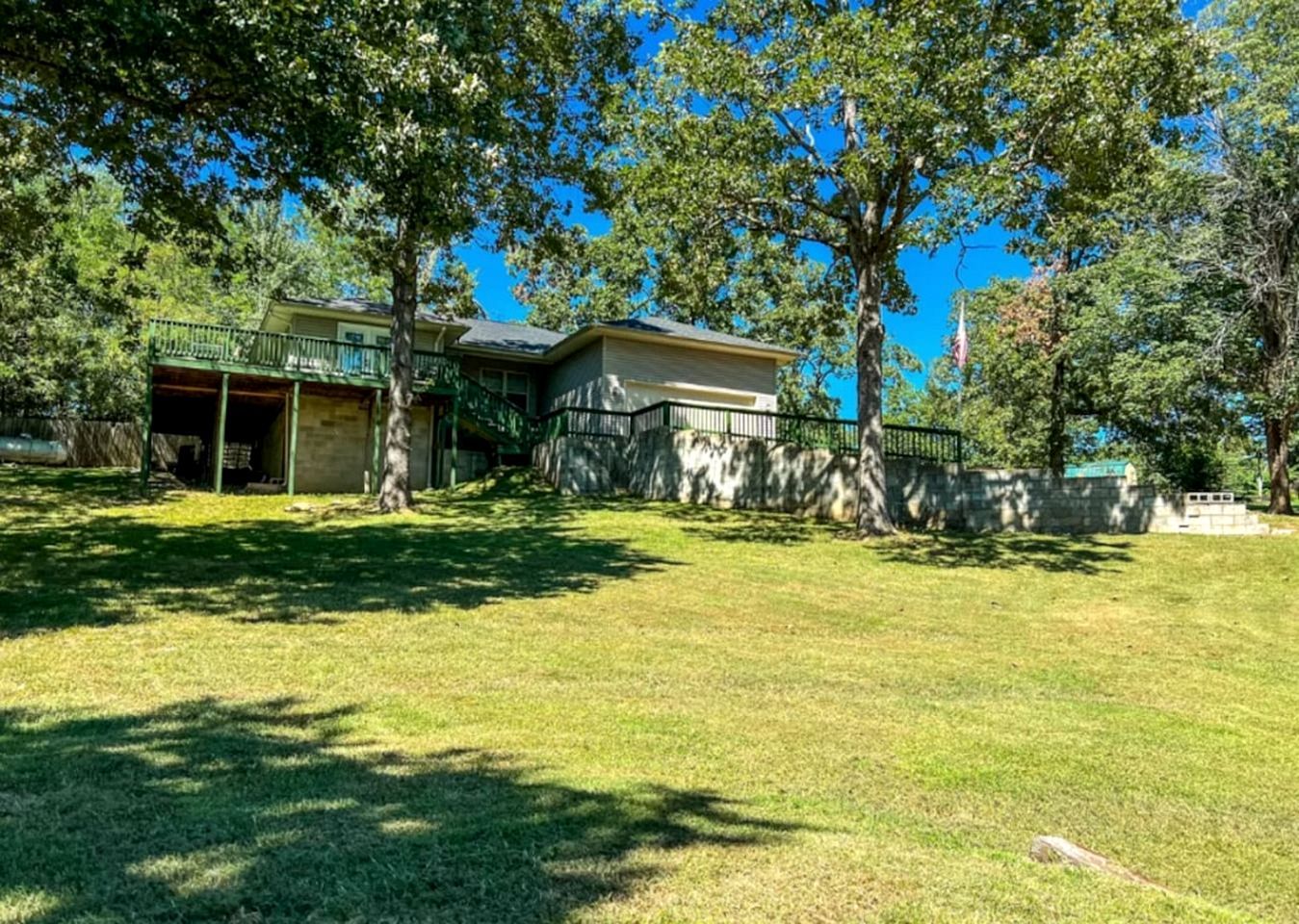 A residential property with a covered patio, a stone wall, and a grassy yard.