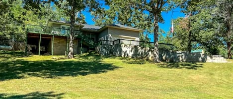 A residential property with a covered patio, a stone wall, and a grassy yard.