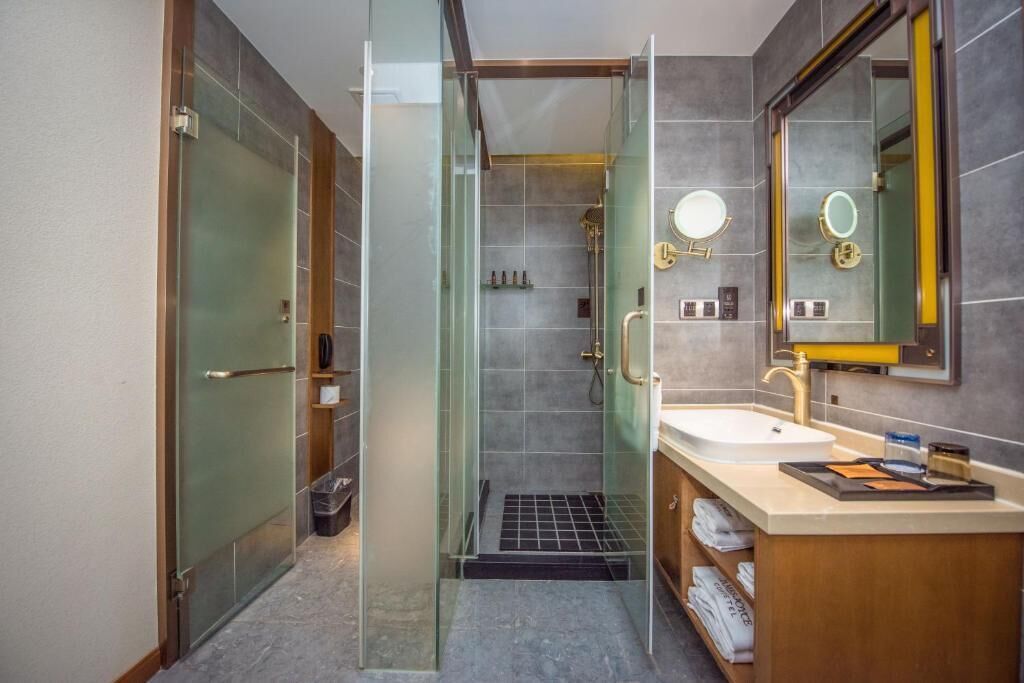 A modern bathroom with a glass-enclosed shower, a sink with a gold faucet, and a mirror with a gold frame.