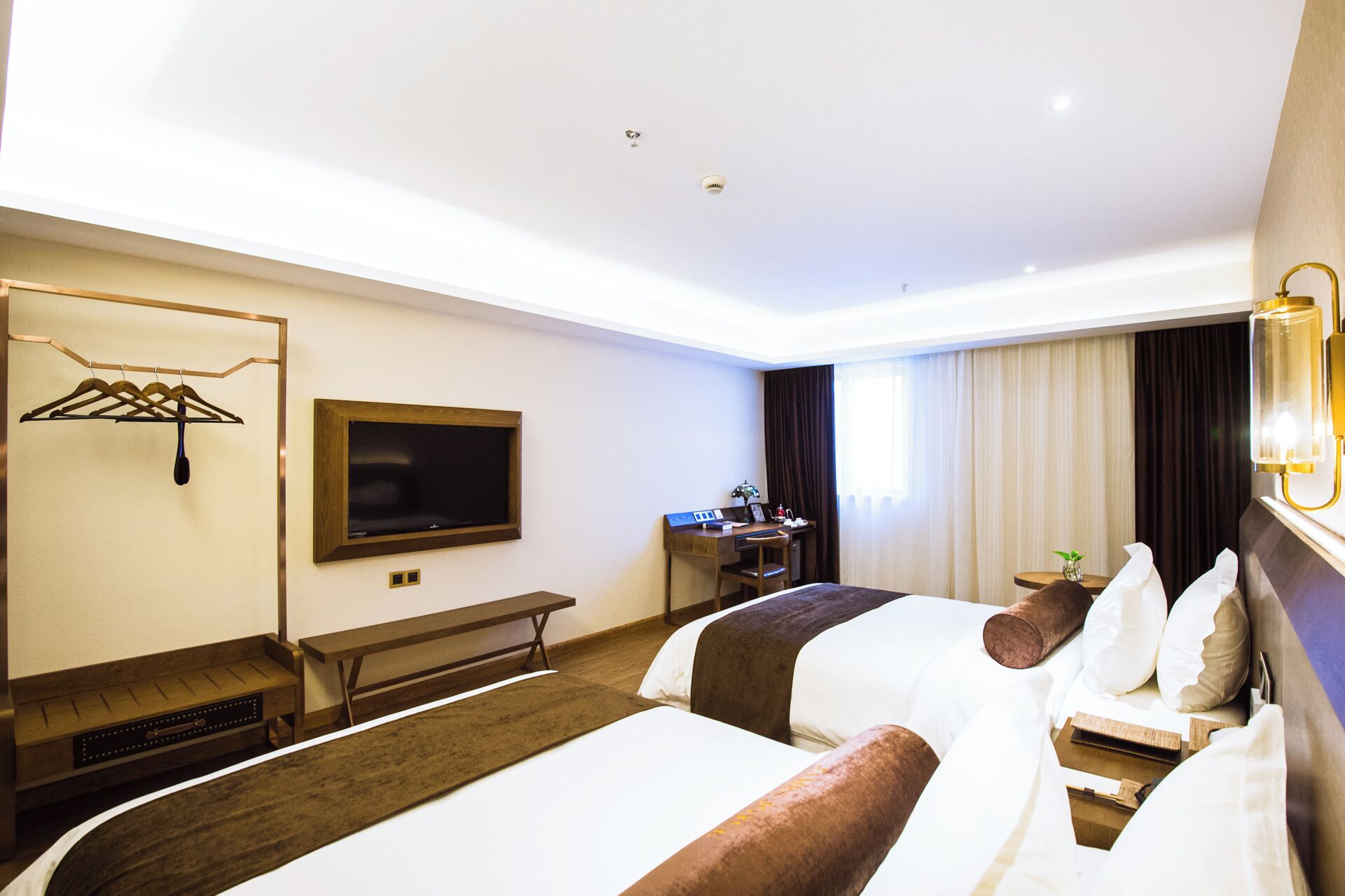 Ein Hotelzimmer mit zwei Betten, einem Schreibtisch, einem Fernseher und einer Sitzecke.