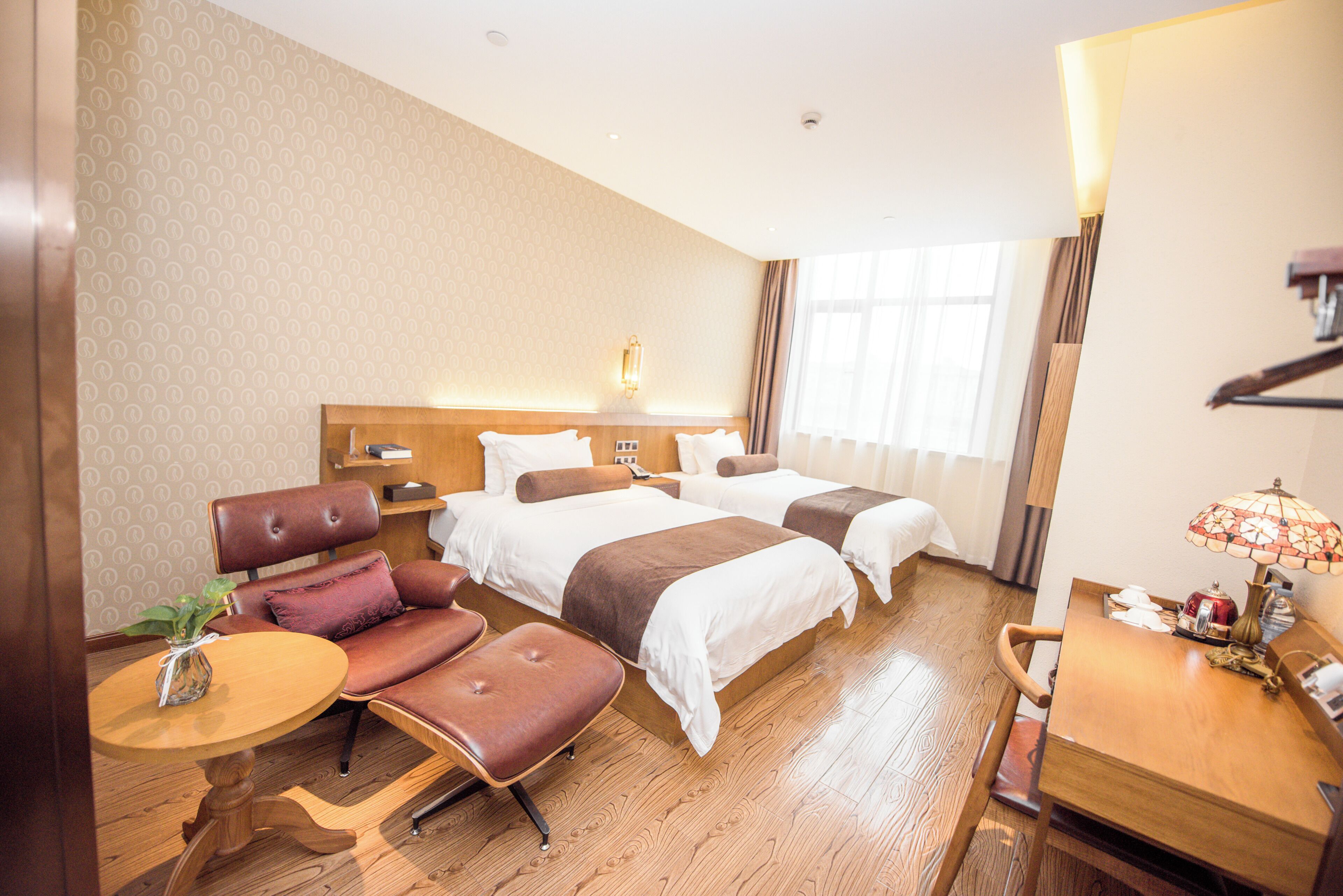 Habitación de hotel con dos camas, un sofá, una mesita y una lámpara.
