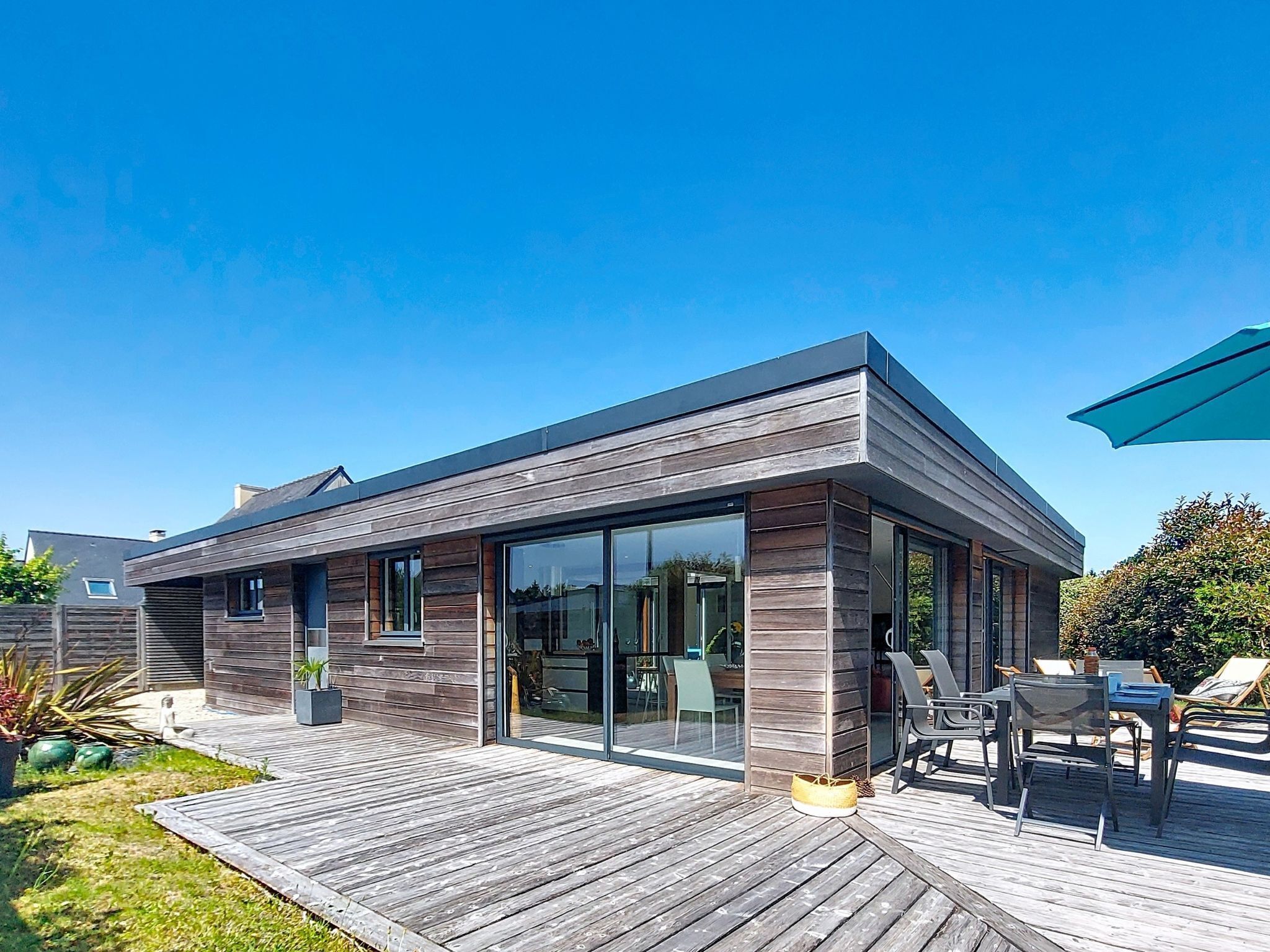 A modern house with a deck, large windows, and a patio area.