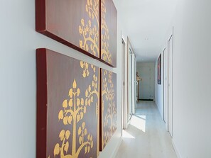 Een hal met een modern ontwerp, met een patroon op de muur en uitzicht op een andere kamer.