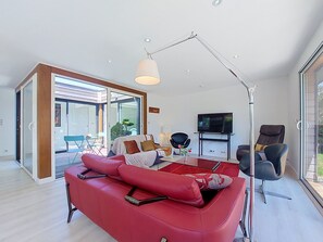 Ein modernes Wohnzimmer mit einem roten Sofa, einem Couchtisch und einem Fernseher.