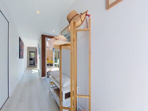 Ein Korridor mit Etagenbetten und einer Holzleiter, der zu einem Raum mit einem Bett und einem Fenster führt.