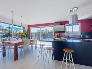 A modern kitchen with a central island, bar stools, and a dining area with a table and chairs. - Bois et Lumière by Interhome (Sainte Marine - Combrit)