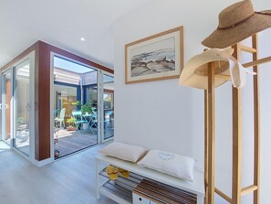 A modern interior with a sliding glass door leading to an outdoor patio, a white bench with cushions, and a framed picture on the wall. - Bois et Lumière by Interhome (Sainte Marine - Combrit)
