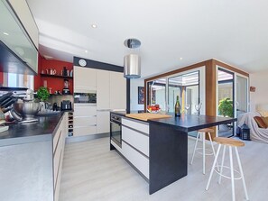 Eine moderne Küche mit Kochinsel, Edelstahlgeräten und einem großen Fenster.