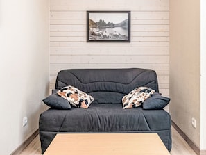 A dark grey sofa with two patterned cushions, a framed picture on the wall, and a wooden coffee table in front. - Les Chalets d'Ax by Interhome (Ax-Les-Thermes)