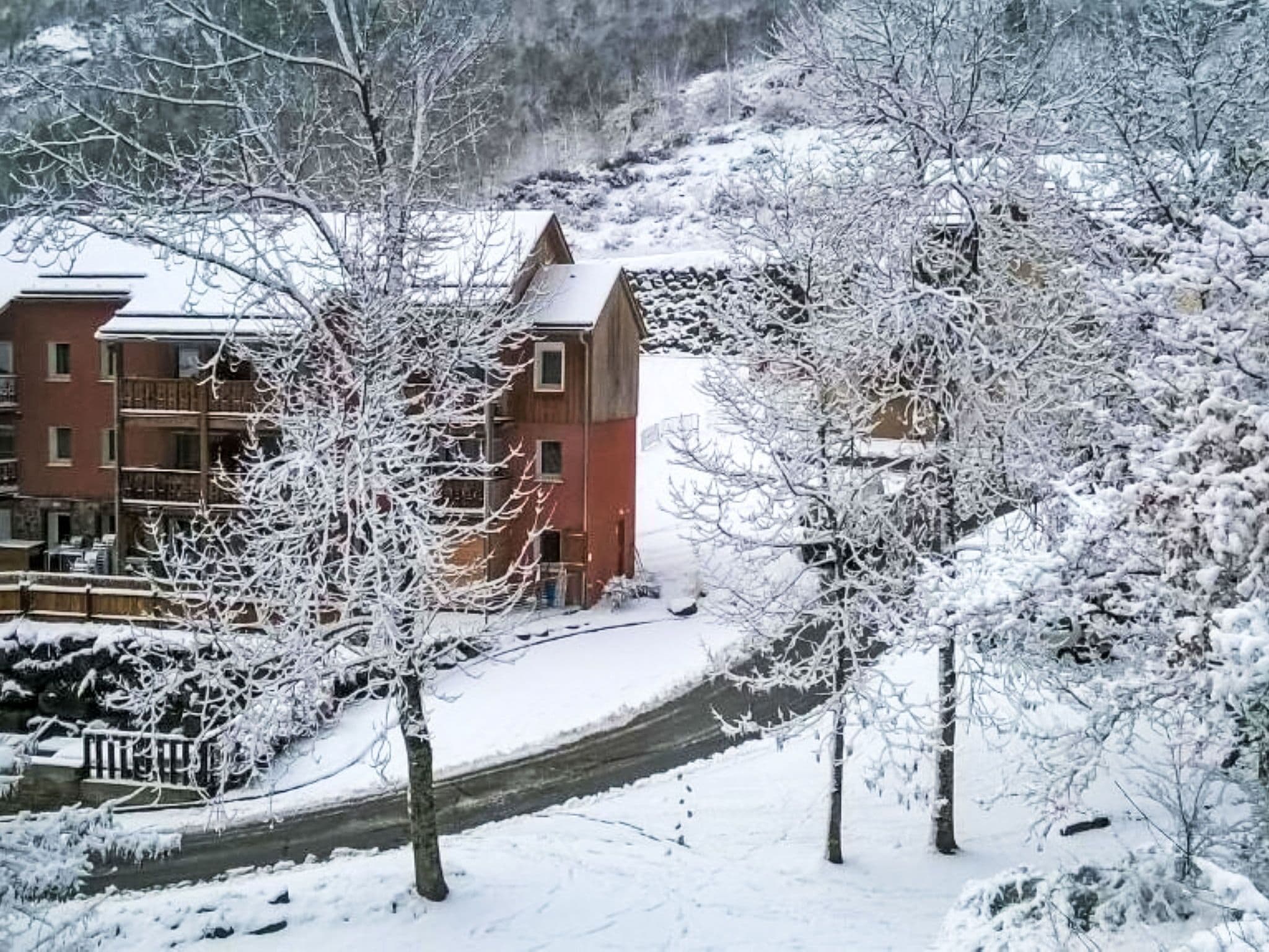 A snow-covered building with multiple windows and a visible balcony.