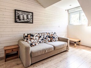A room with a sofa, a small wooden table, a picture on the wall, and a window. - Les Chalets d'Ax by Interhome (Ax-Les-Thermes)