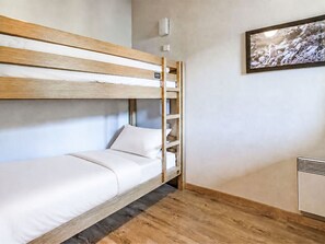 Un letto a castello con una testiera in legno, un materasso bianco e una piccola unità con scaffali.