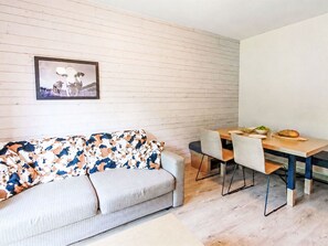 Ein modernes Wohnzimmer mit einer Couch, einem Esstisch mit Stühlen und einem gerahmten Bild an der Wand.