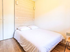 Ein Schlafzimmer mit einem Bett, weißer Bettwäsche, einem Holz-Kopfteil und Holzdielen.