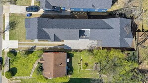 Eine Luftaufnahme eines Wohngebiets mit einem Haus mit Schrägdach, Garage und kleinem Vorgarten.
