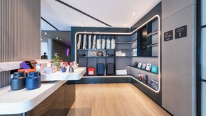 A modern hotel lobby with a wooden floor, a reception desk, and a wall with storage shelves. - Atour Hotel, Hisense Plaza, May Fourth Square, Qingdao (Qingdao)