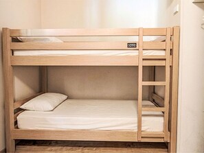 Ein Stockbett mit Holzrahmen, einer Matratze und einem Kopfkissen.