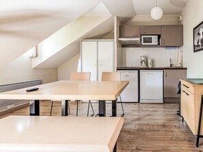 Eine moderne Küche mit Essbereich, ausgestattet mit einem Holztisch, Schränken und einer Mikrowelle.