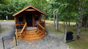 A wooden cabin with a porch, steps, and a fenced area.
