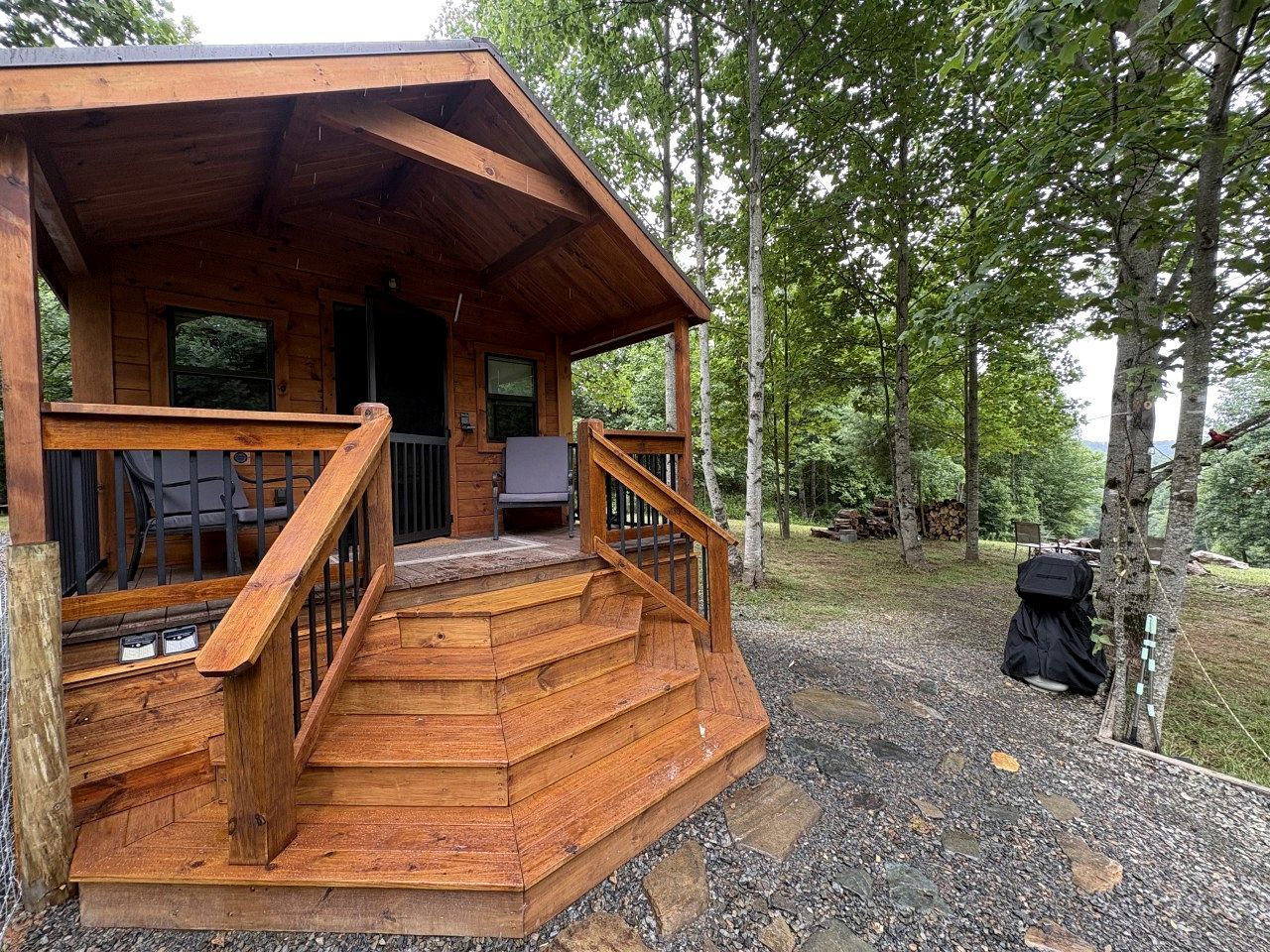 A wooden cabin with a porch, outdoor seating, and a grill.