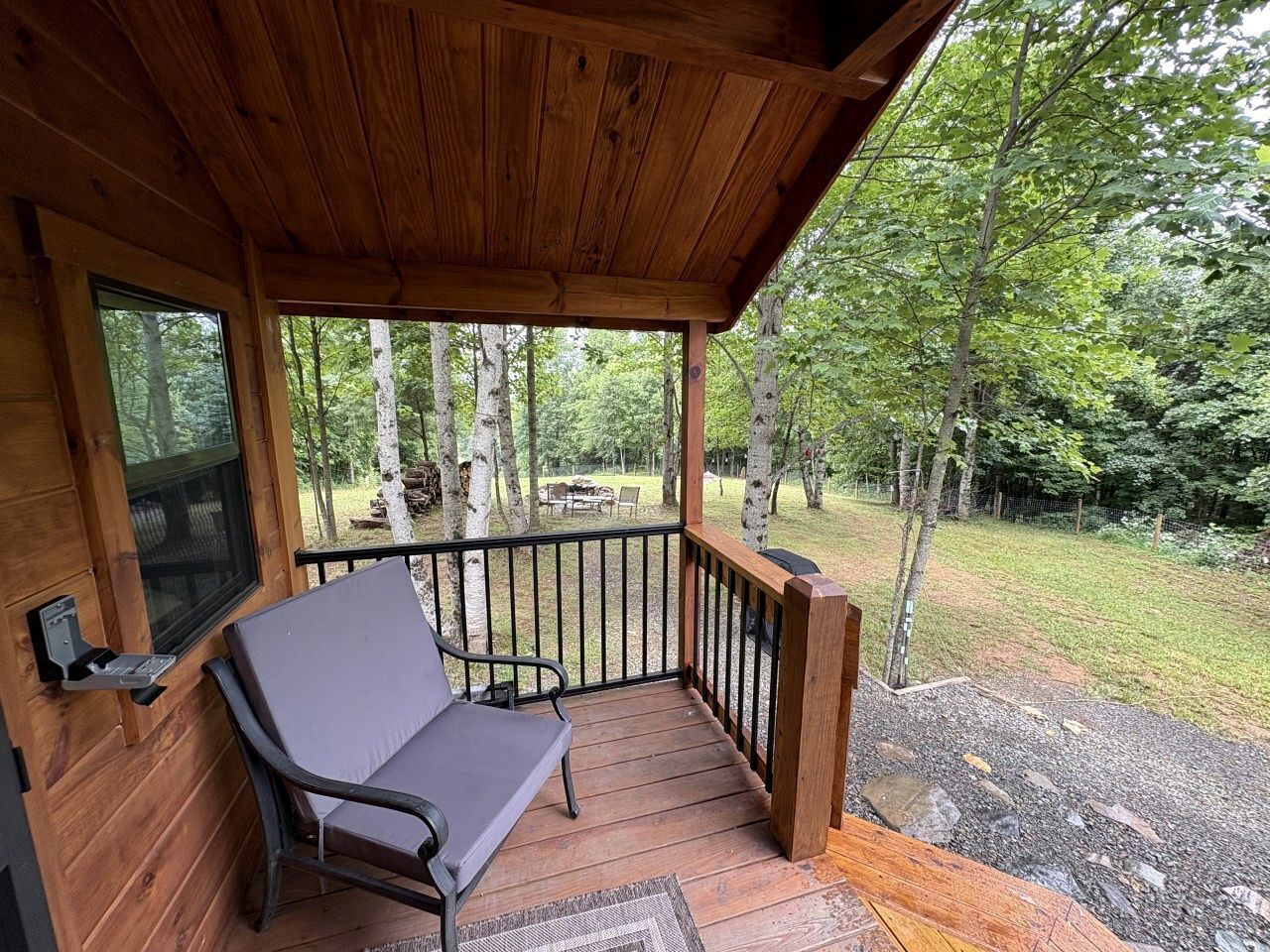 A wooden deck with a bench, a grill, and a view of a forested area.