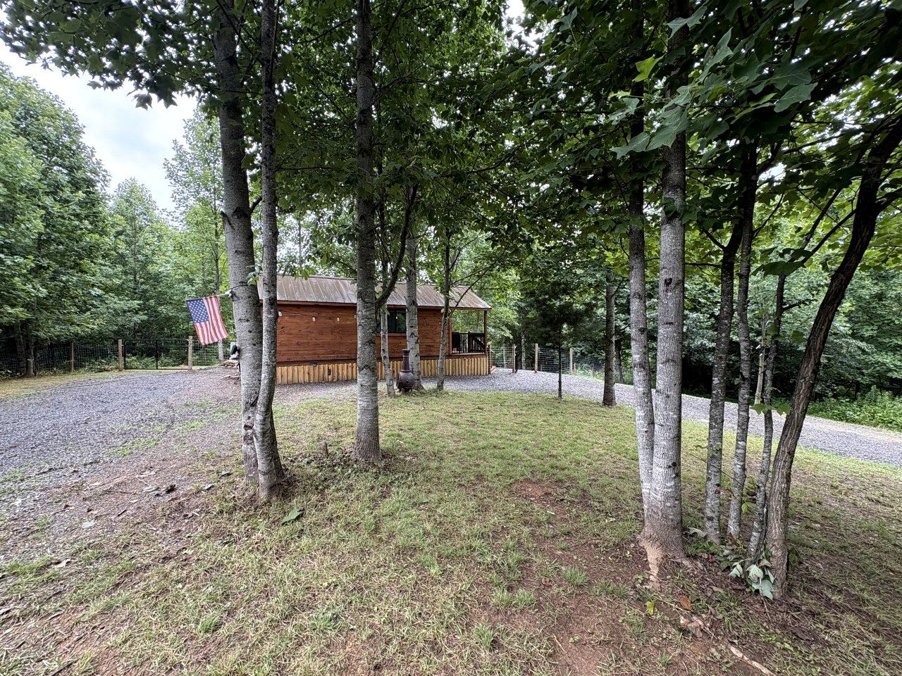 A cabin surrounded by trees, with a gravel path leading to it.