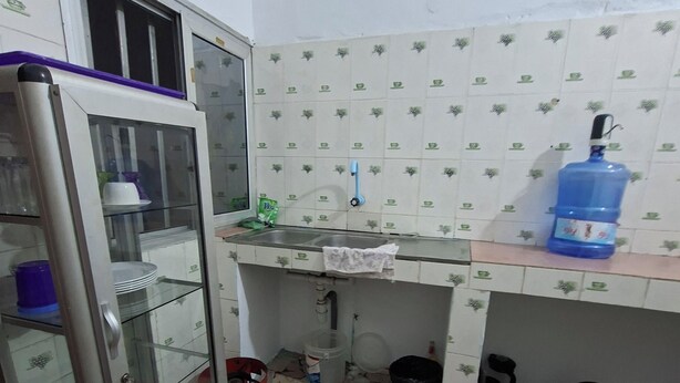 Cocina compacta con refrigerador, pileta y salpicadero de azulejos.