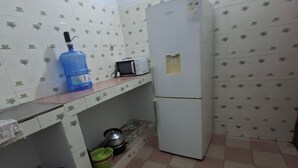 Una pequeña cocina con refrigerador, microondas y dispensador de agua en la encimera.