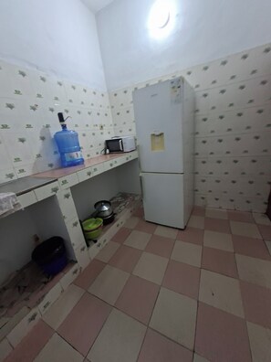 A small kitchen with a refrigerator, microwave, and a water dispenser on the counter.