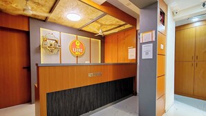 Un mostrador de recepción con un cartel que dice 'The Lions Hotel', un ventilador de techo y una cámara de seguridad.