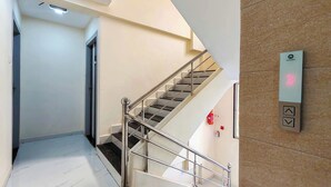 A modern interior with a staircase, a wall-mounted elevator, and a fire extinguisher.