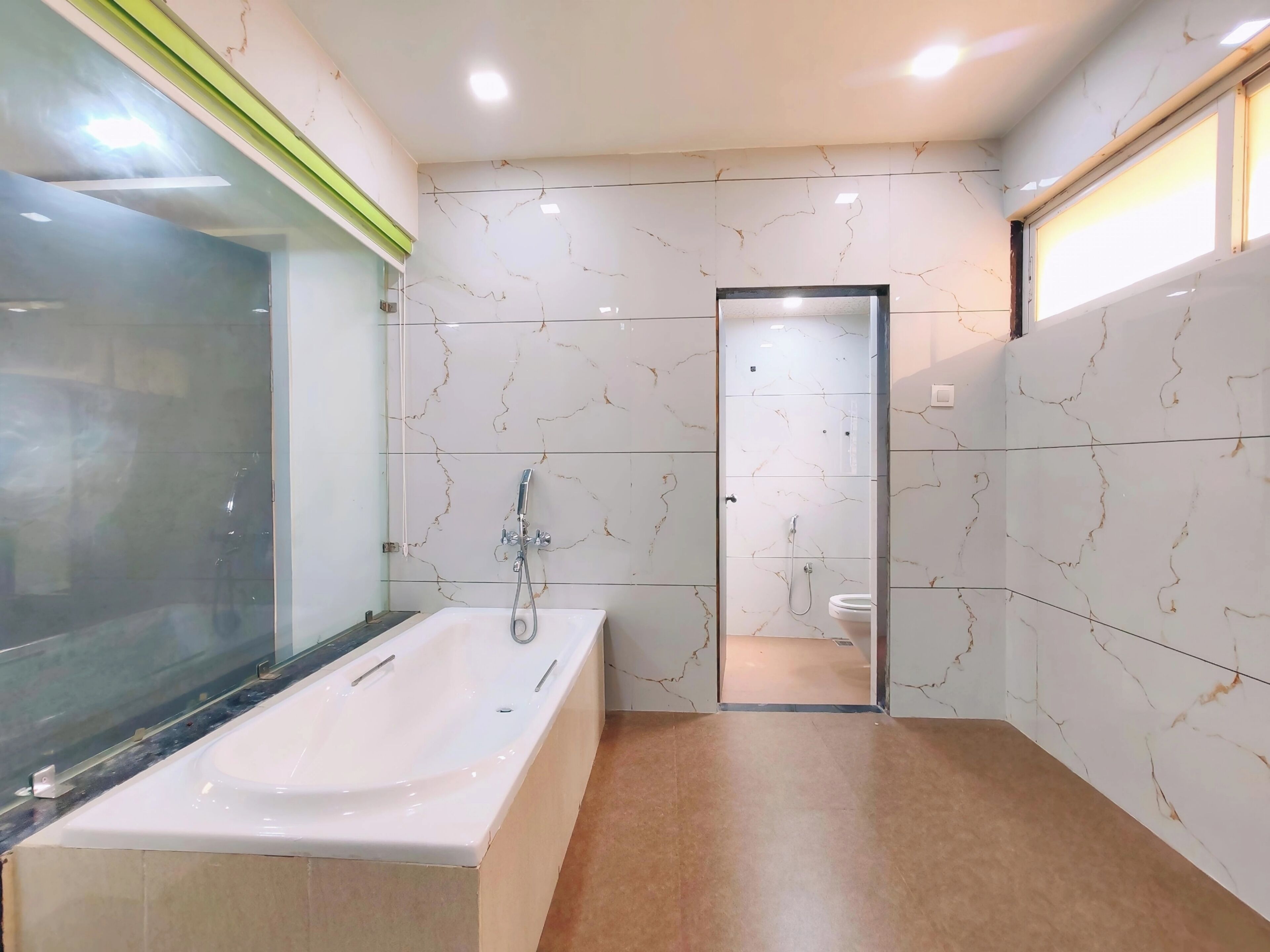 A modern bathroom with a glass-enclosed shower, a white bathtub, and marble-patterned walls.