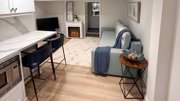 A modern kitchen with white cabinets, a marble countertop, and a dining area with blue chairs. - Executive 1BR Suite | Express Transit to Downtown & Airport | Fast Wi-Fi (Toronto)