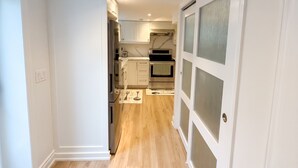 A modern kitchen with white cabinets, a stainless steel refrigerator, and a wooden floor. - Executive 1BR Suite | Express Transit to Downtown & Airport | Fast Wi-Fi (Toronto)