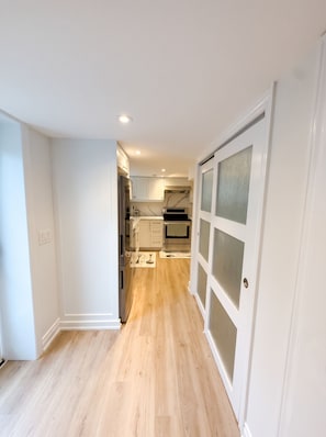 A modern kitchen with white cabinets, a stainless steel refrigerator, and a wooden floor.