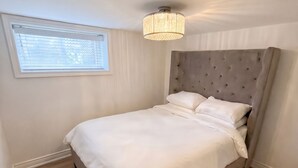 A bedroom with a bed, a window with blinds, a ceiling light fixture, and a fluffy rug. - Executive 1BR Suite | Express Transit to Downtown & Airport | Fast Wi-Fi (Toronto)