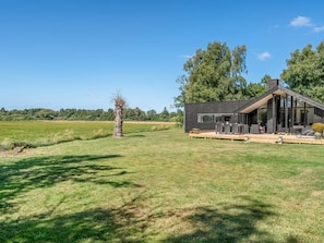 A modern house with a deck, surrounded by a grassy field and trees. - "Tameran" -  from the sea by Interhome (Hals)