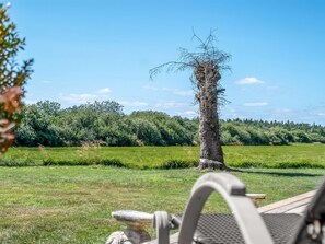 A tree with a nest in its branches, a grassy field, and a clear sky. - "Tameran" -  from the sea by Interhome (Hals)