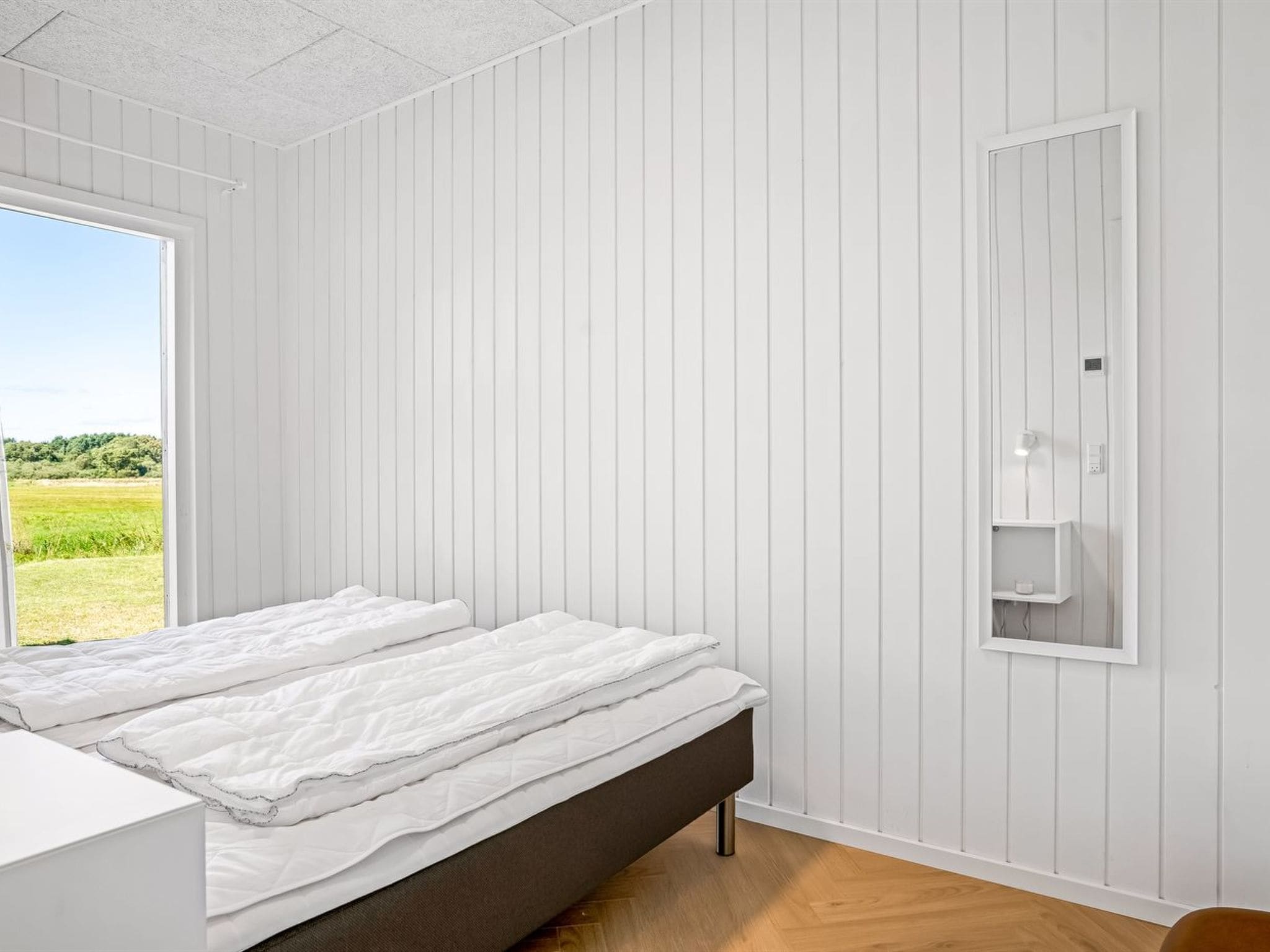 Ein Schlafzimmer mit einem Bett, einem Fenster und einem an der Wand befestigten Regal.