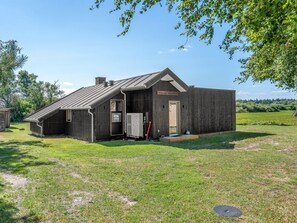 A rustic wooden building with a sloped roof, a small porch, and a door labeled 'Cask & Barrel Restaurant.' - "Tameran" -  from the sea by Interhome (Hals)