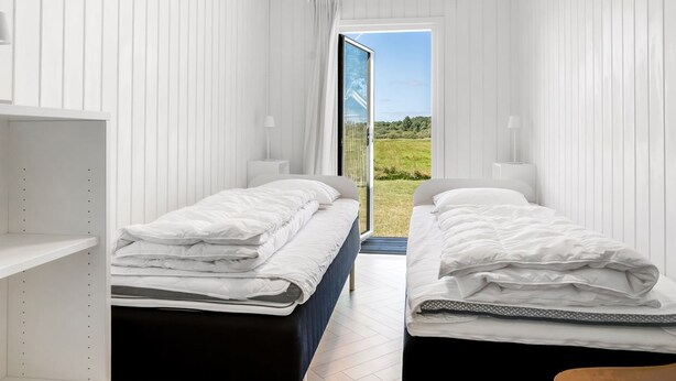 Ein Schlafzimmer mit zwei Betten, einem Fenster und Blick auf eine grüne Landschaft.