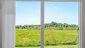 Ein Zimmer mit einer großen Schiebeglasdoor zu einem grünen Feld.