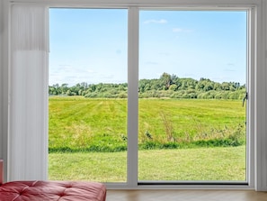A room with a large sliding glass door leading to a grassy field. - "Tameran" -  from the sea by Interhome (Hals)