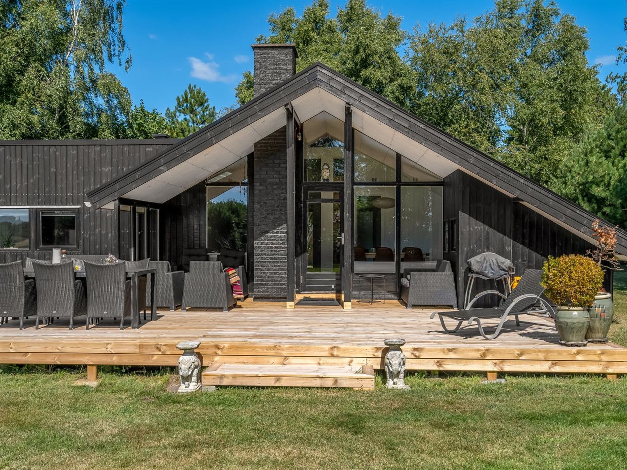A modern house with a sloped roof, large glass windows, and a wooden deck.