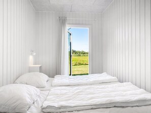 Un dormitorio con dos camas, una ventana y vistas a un campo verde.