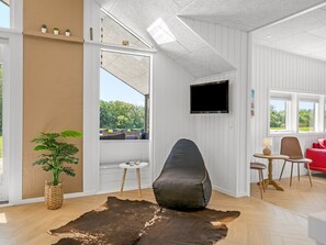 A modern living room with a large window, a mounted TV, a leather chair, and a red sofa. - "Tameran" -  from the sea by Interhome (Hals)