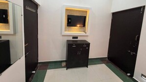 Una habitación con un armario negro, un televisor montado en la pared y una puerta con un diseño texturizado.