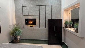 Un interior moderno con un panel de pared empotrado, un gabinete negro y una ventana con plantas en macetas.