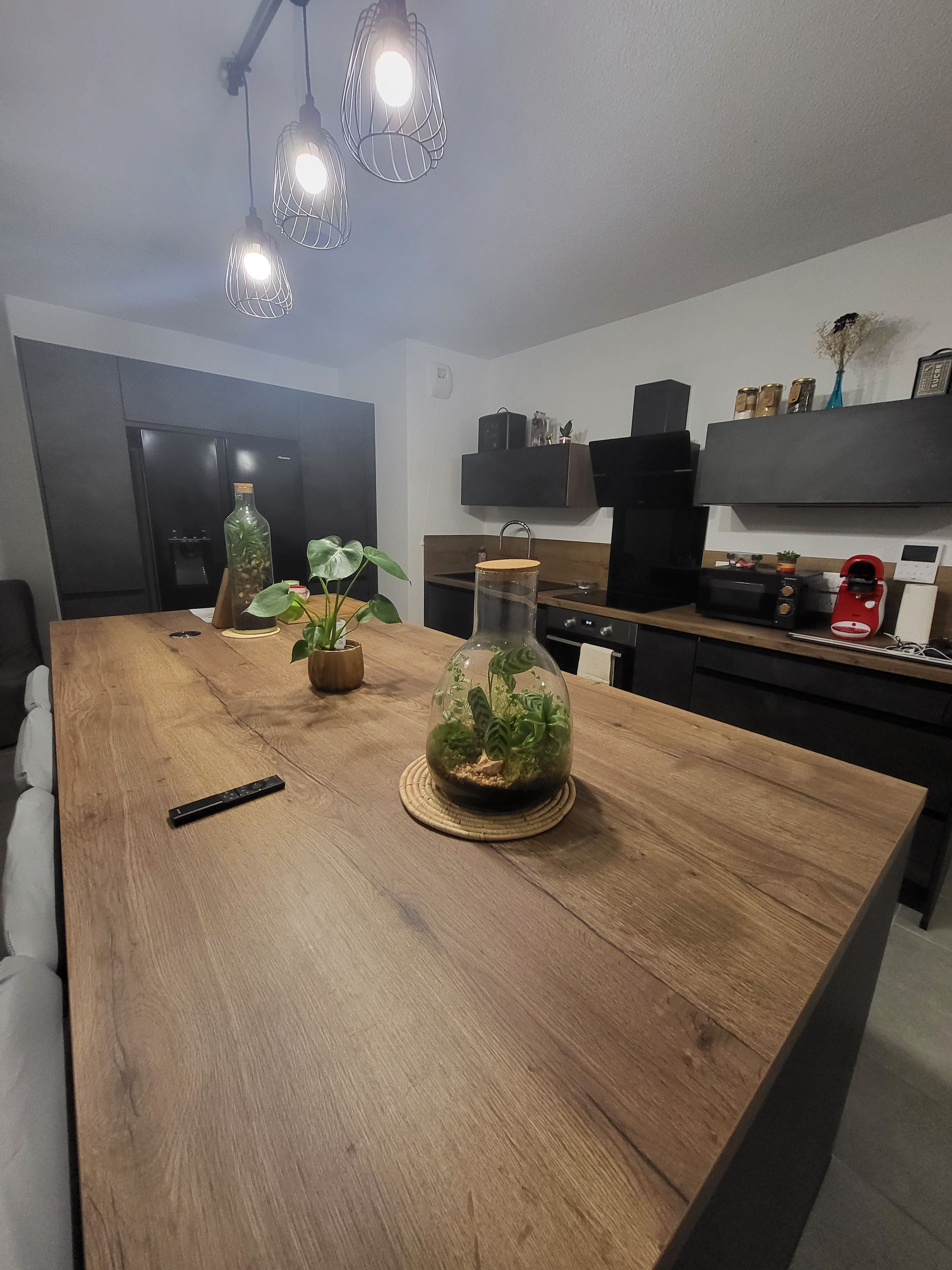 A modern kitchen with a wooden island, a refrigerator, a microwave, and a coffee machine.