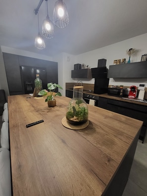 A modern kitchen with a wooden island, a refrigerator, a microwave, and a coffee machine. - Luminous Cocoon - All-Around Comfort - Sleeps 4 to 6 (Montpellier)